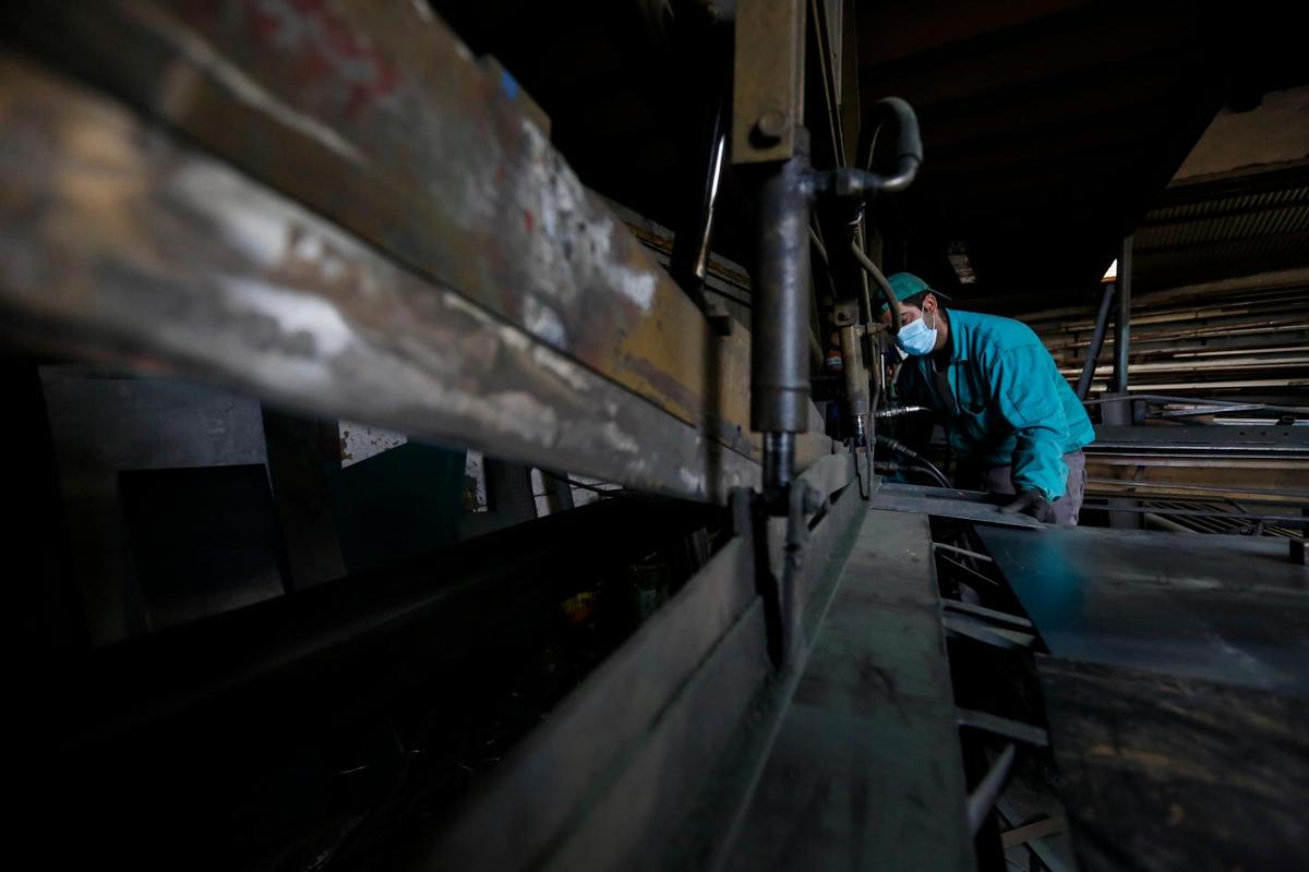 Juan Antonio corta una plancha de metal en la máquina creada y montada por su padre, hace más de treinta años y que siguen utilizando a día de hoy en el taller.