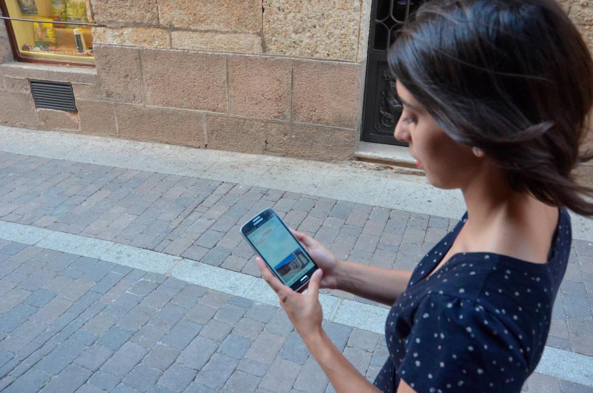 Una chica consulta su móvil por las calles de Miróbriga.