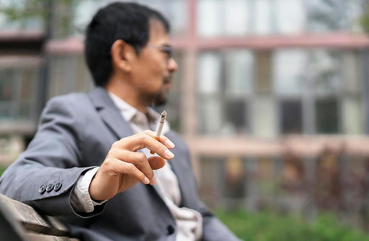 Un hombre fumando un cigarrillo.