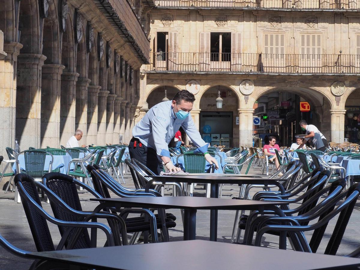 Camarero desinfectando una de las mesas en una terraza.