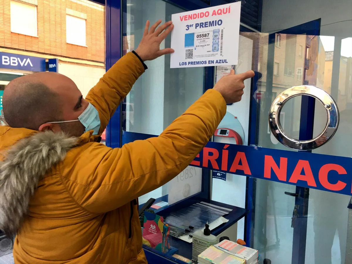 Uno de los responsables de Los Manolos coloca el cartel con el tercer premio de El Niño