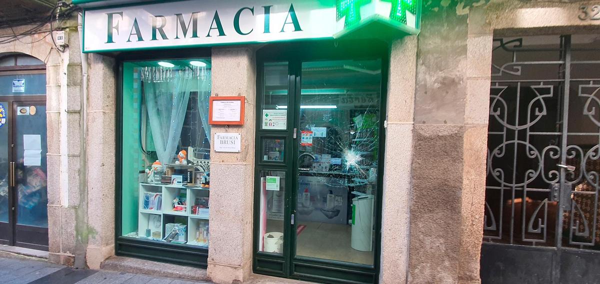 Imagen de la puerta de la farmacia de la calle Mayor de Béjar con el cristal de su puerta reventado I TEL