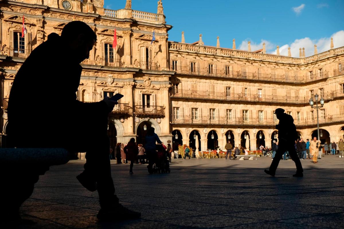 Una persona consultando su teléfono móvil en la Plaza Mayor.