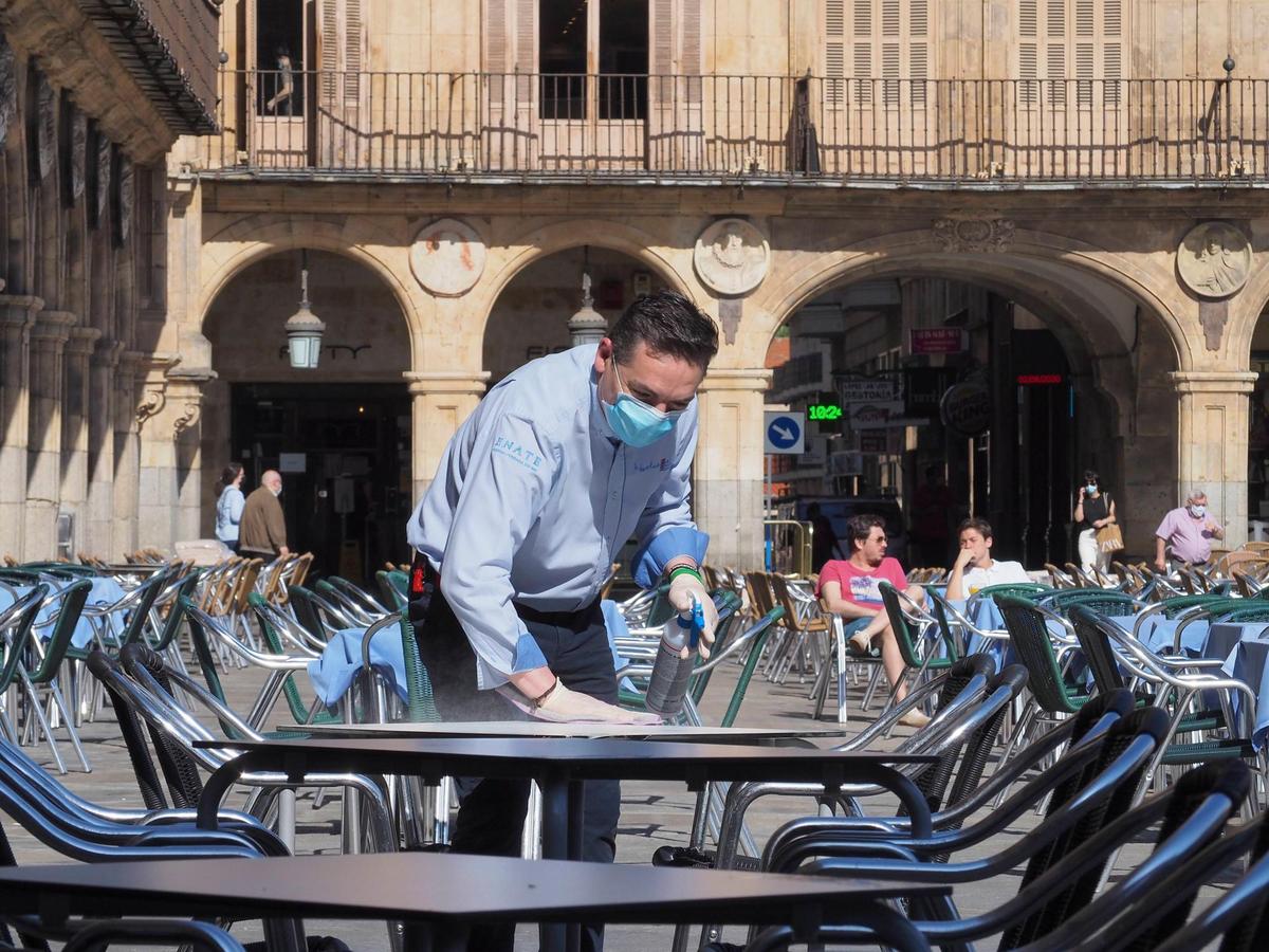 Un camarero desinfecta una terraza en la Plaza Mayor.