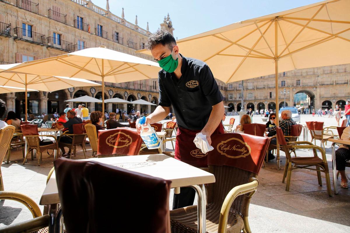 Un camarero limpia la mesa de una terraza de la Plaza Mayor.