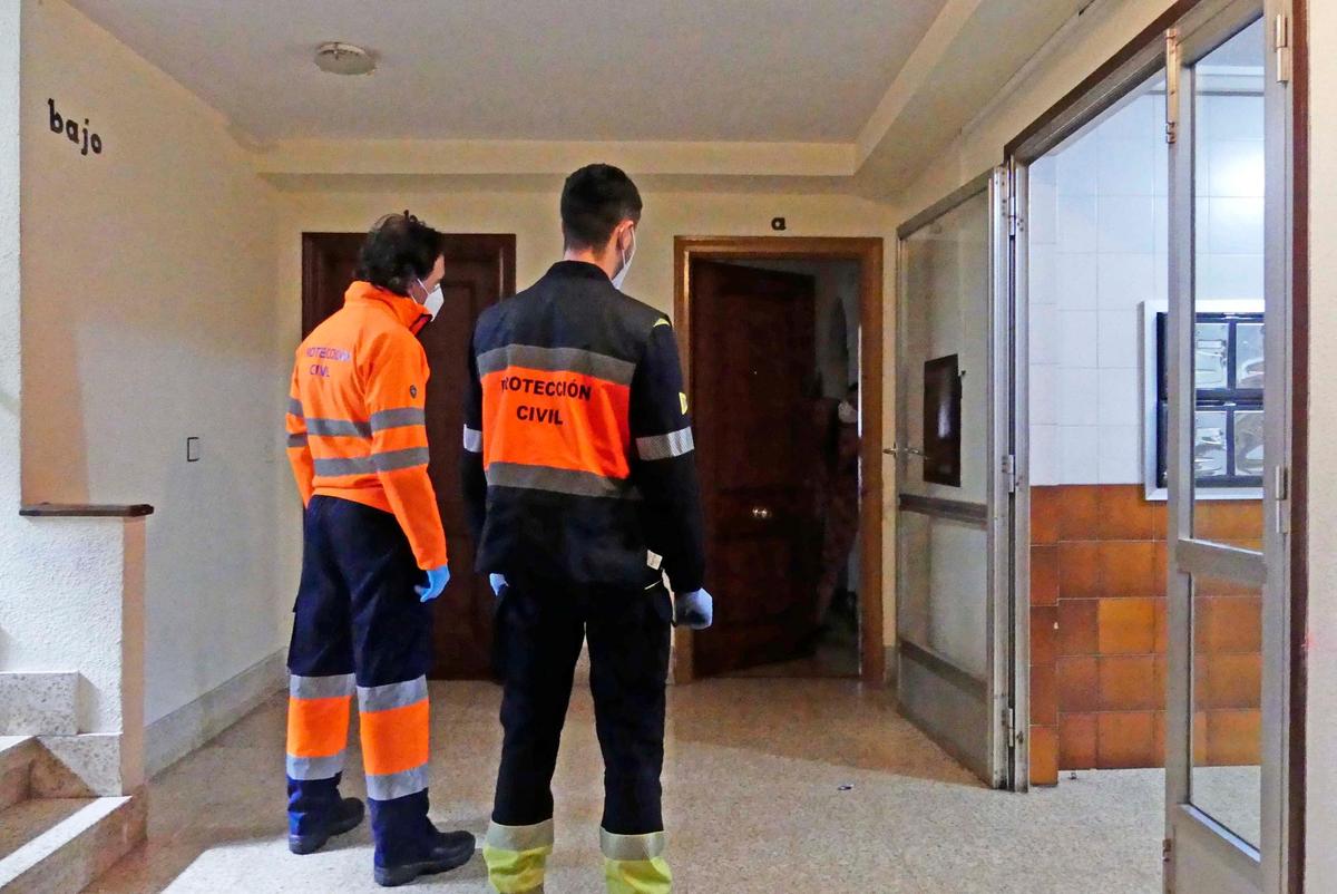 Dos voluntarios de Protección Civil visitan a una vecina confinada.