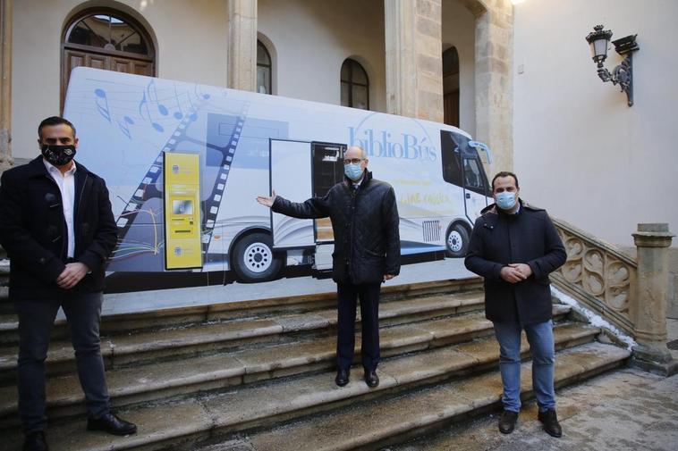 Antonio Labrador, Javier Iglesias y David Mingo junto a una recreación del bibliobús con cajero.