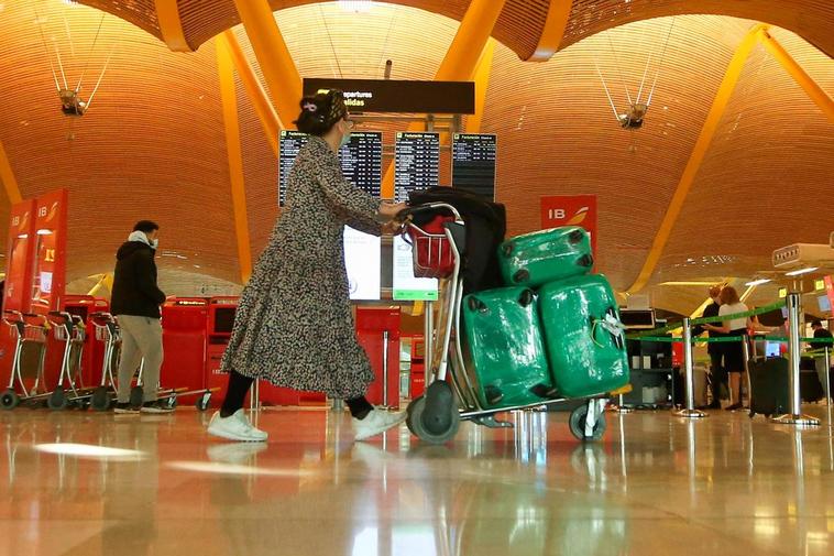 Una mujer camina con varias maletas en un carro en la terminal T4 del Aeropuerto Adolfo Suárez Madrid-Barajas.