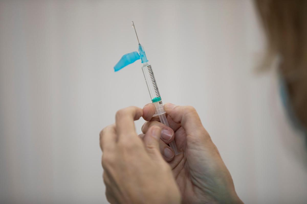 Un sanitario se dispone a poner una vacuna de Pfizer.