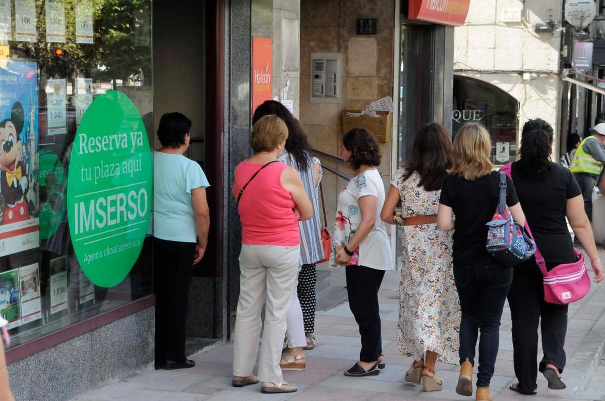 Varias personas haciendo cola frente a una agencia de viajes