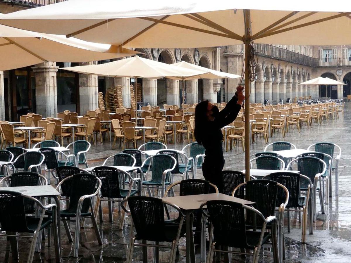 Una camarera recoge un toldo en la Plaza Mayor