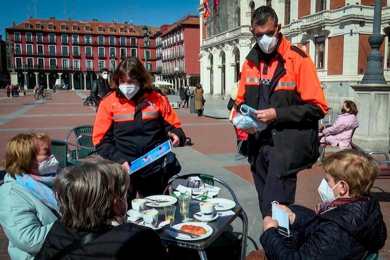 Voluntarios de Protección Civil informan sobre las medidas sanitarias a tres clientas de una terraza de Valladolid