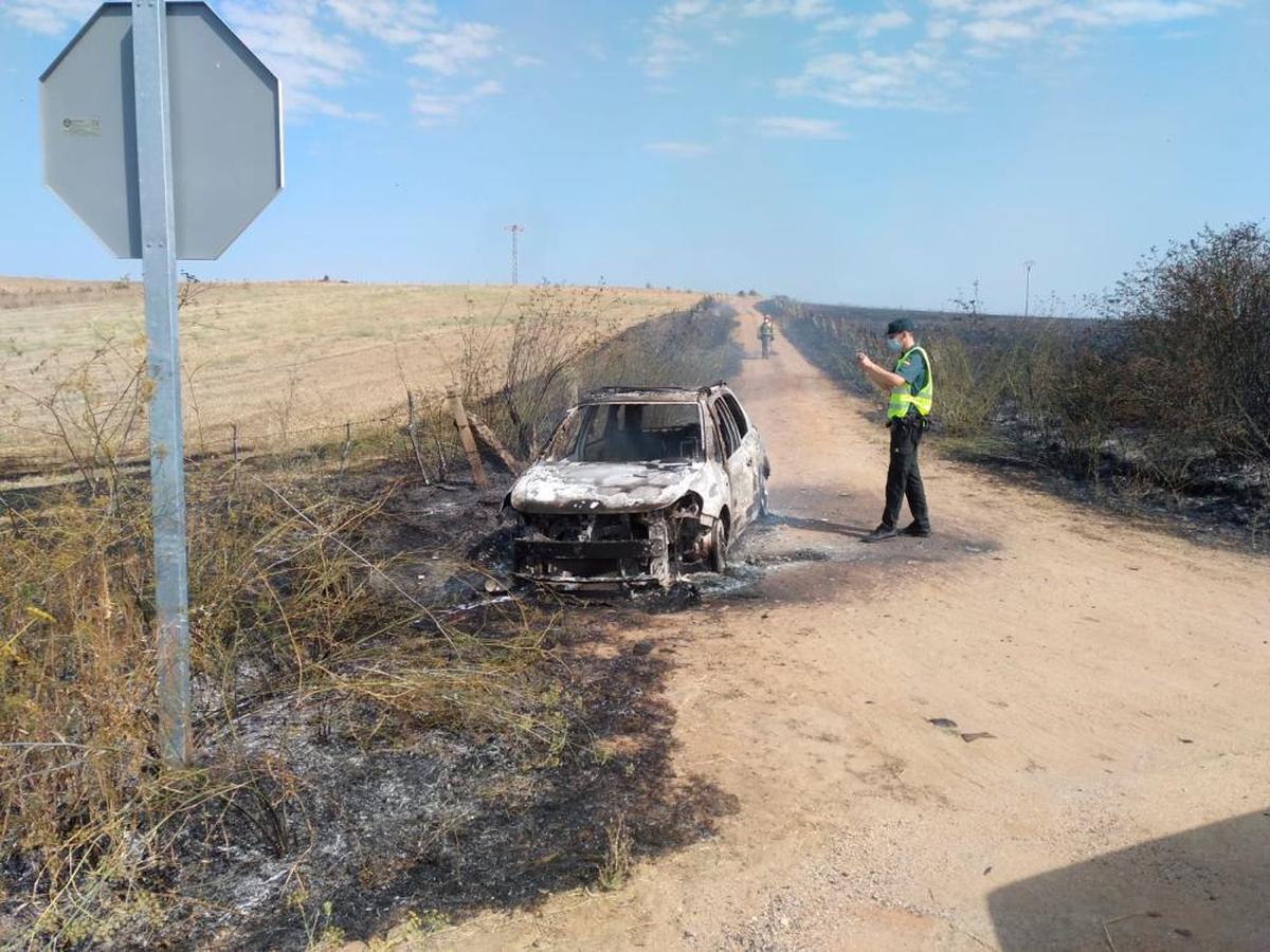 Un agente de la Guardia Civil observa el vehículo calcinado.