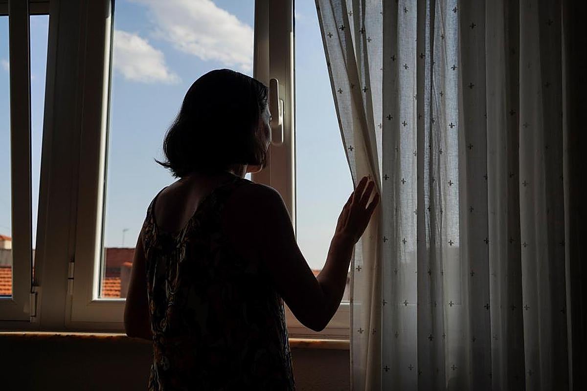 Una joven contempla el exterior desde la ventana de su casa.