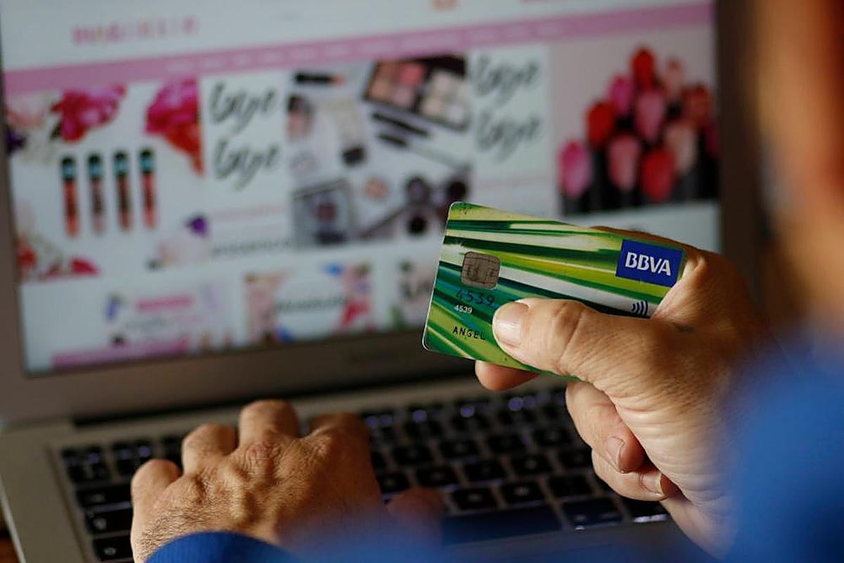 Un hombre usa su tarjeta de crédito para comprar en una página web.