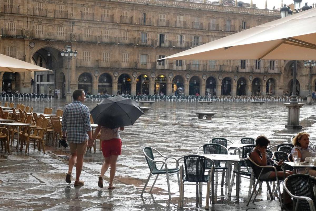 Dos turistas bajo la lluvia en la Plaza Mayor