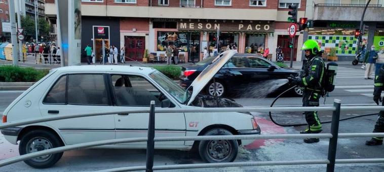 Bomberos junto al vehículo que echó a arder en la avenida de Portugal.