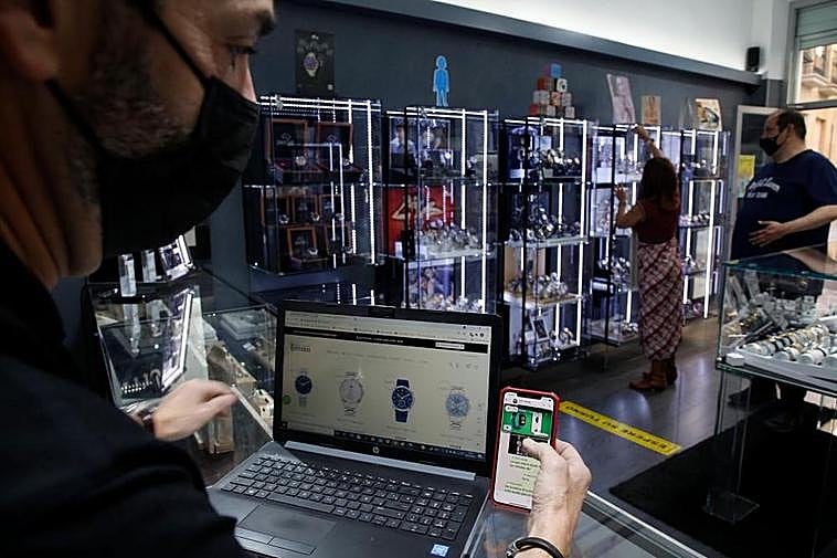 Un comerciante consulta su página web en el portátil y sus redes en su móvil.