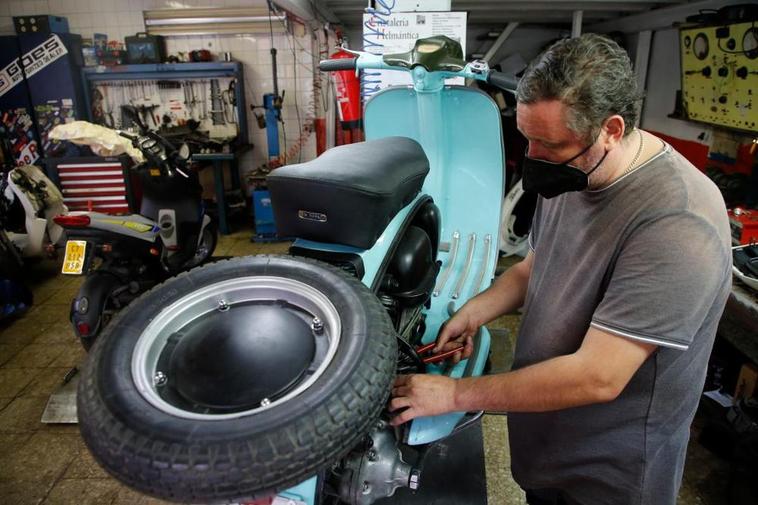 Un autónomo salmantino arregla una motocicleta en su taller.