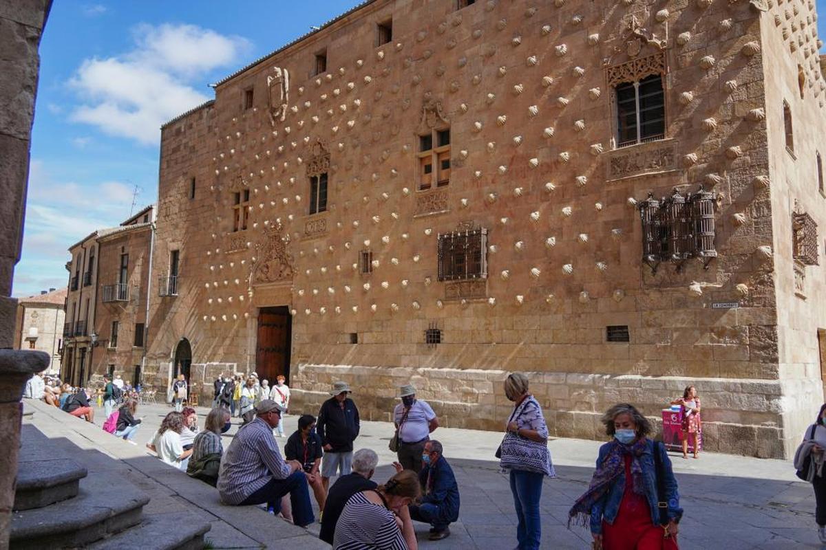 Varios turistas descansan junto a la Casa de las Conchas.