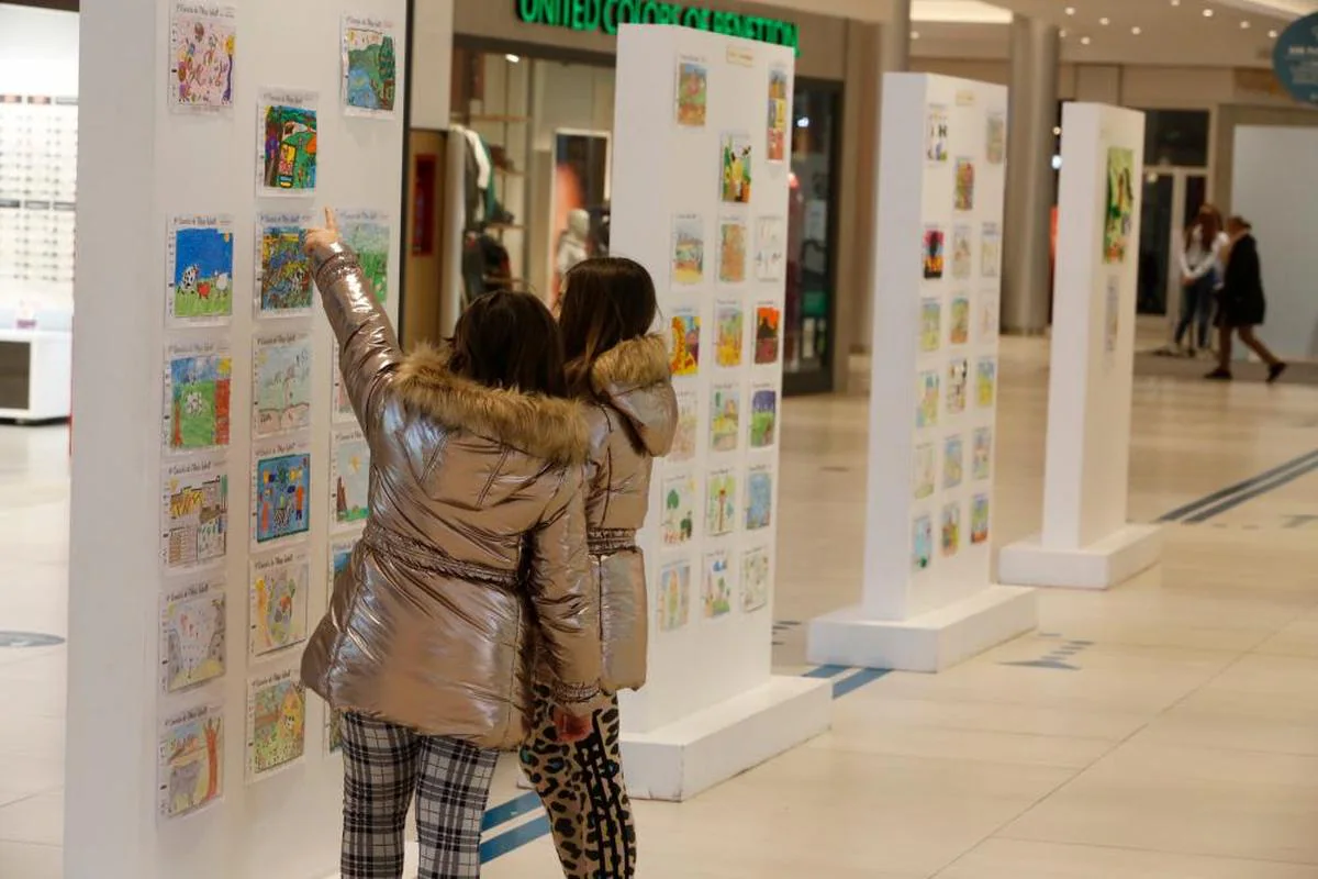 Dos niñas observando la exposición de dibujos ganadores y finalistas de la pasada edición.