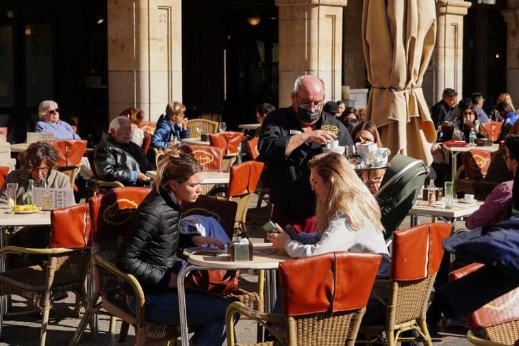 Un camarero sirviendo a dos clientas en una terraza de la Plaza Mayor