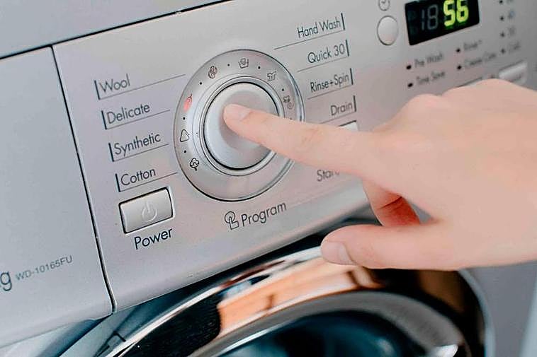 Una persona activa una lavadora.