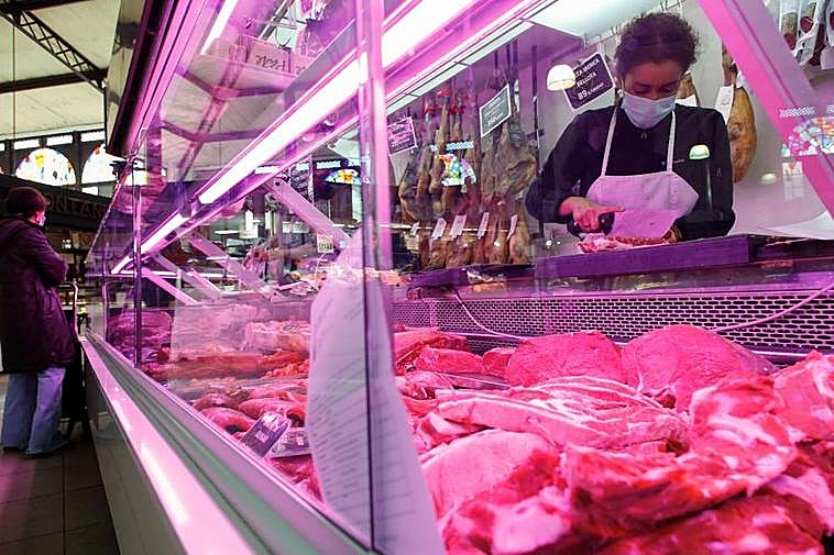 Una carnicera partiendo una pieza.