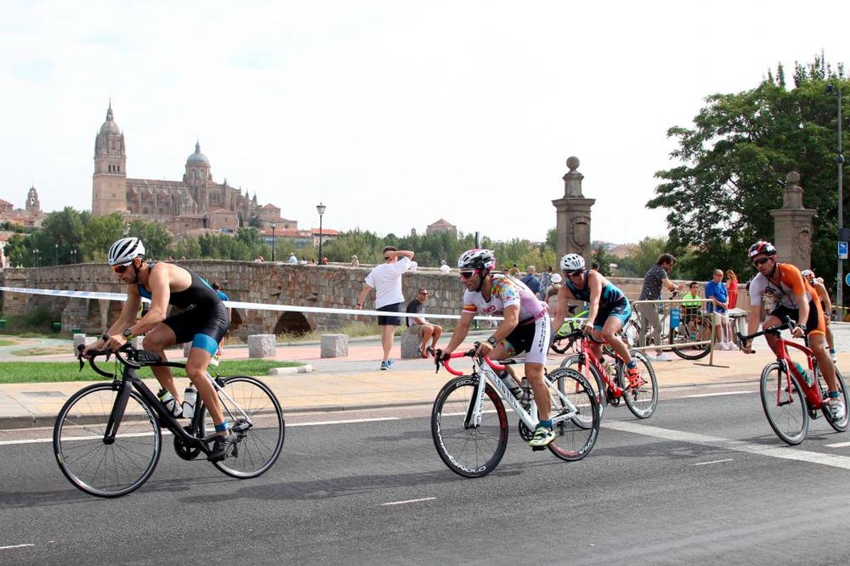 Participantes en el Triatlón de Salamanca recorren el tramo en bicicleta en las inmediaciones del Puente Romano.