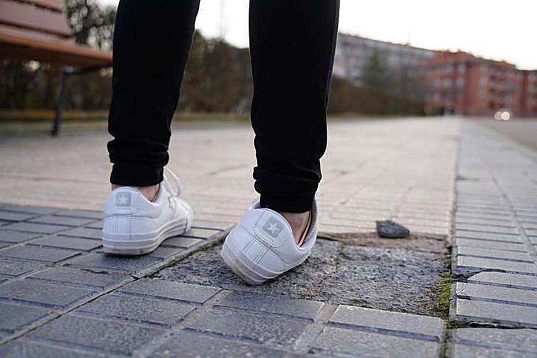 Una mujer da un traspié con una baldosa en mal estado.