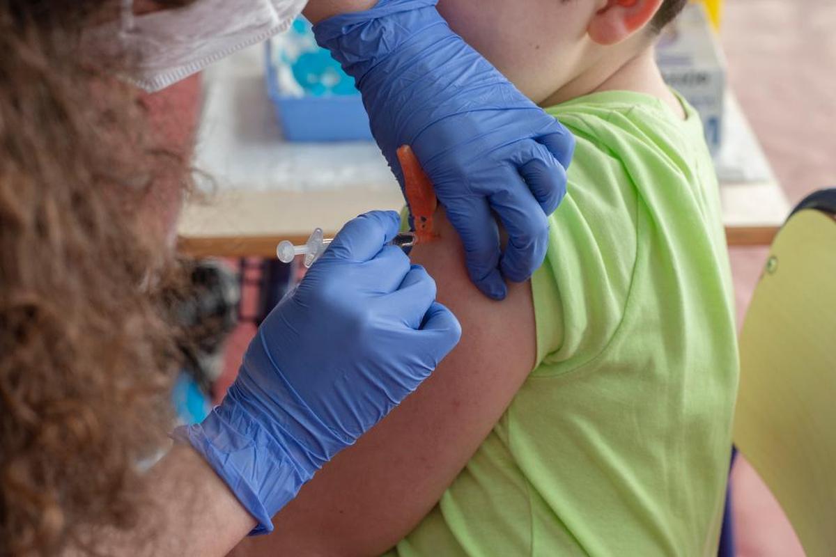 Una sanitaria vacuna a un niño