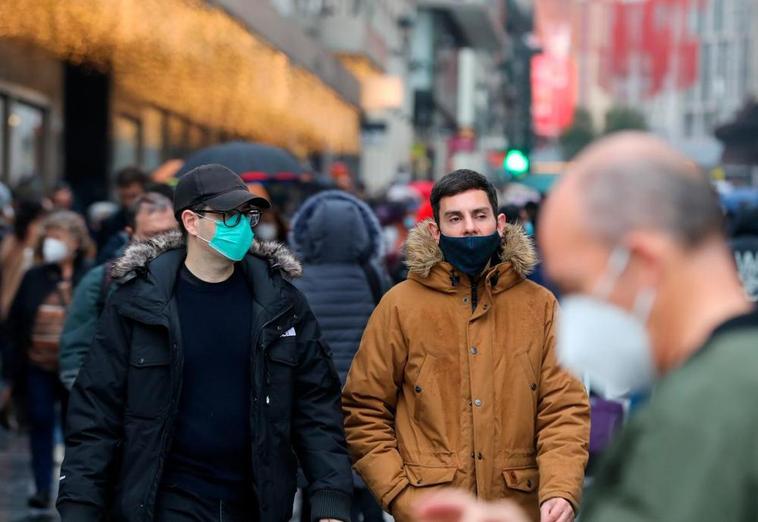 Ciudadanos paseando con la mascarilla puesta.