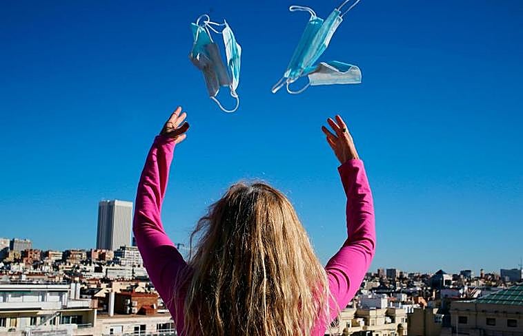 Una mujer tira mascarillas al aire