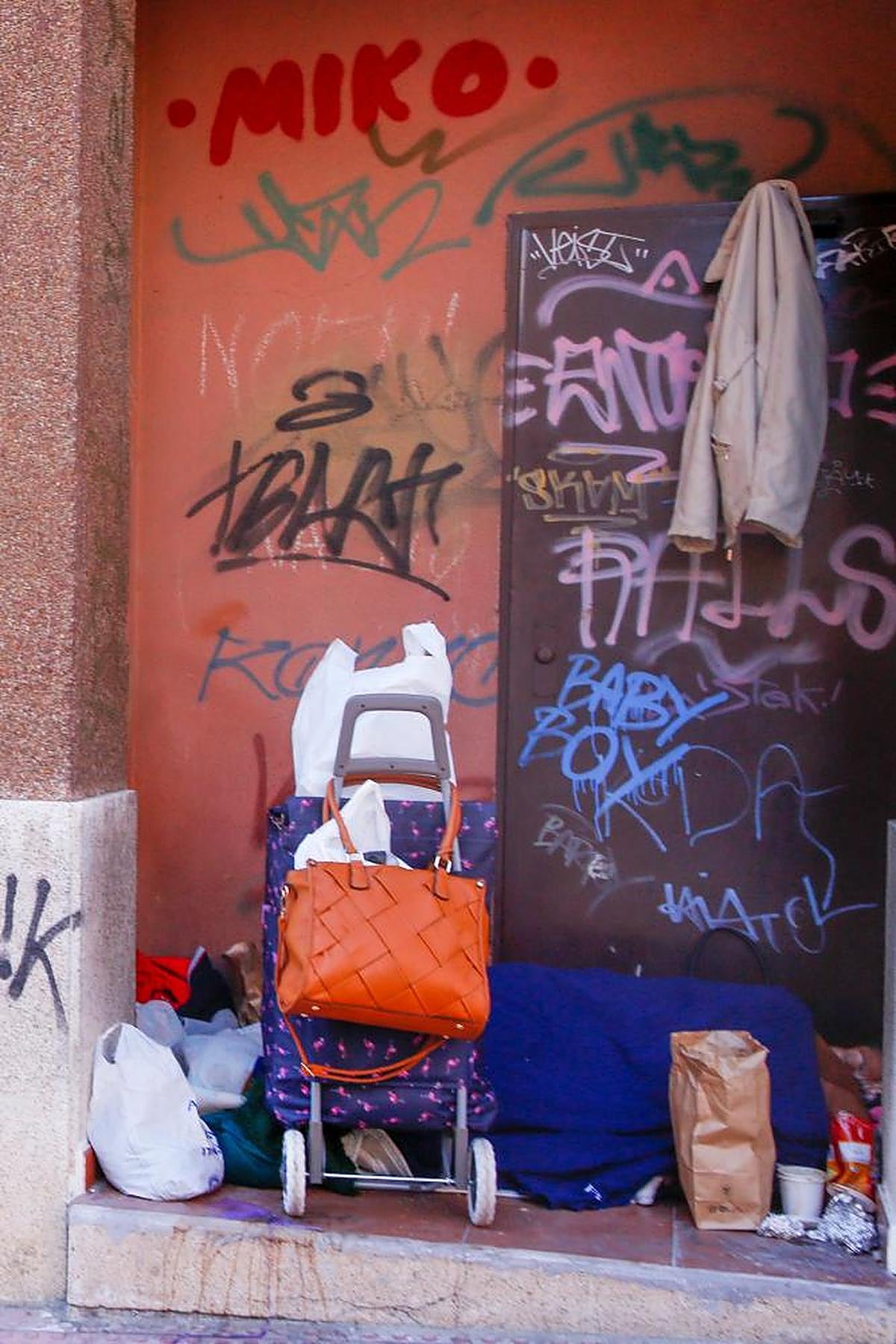 Un sintecho tapado con una manta en el rellano de una puerta