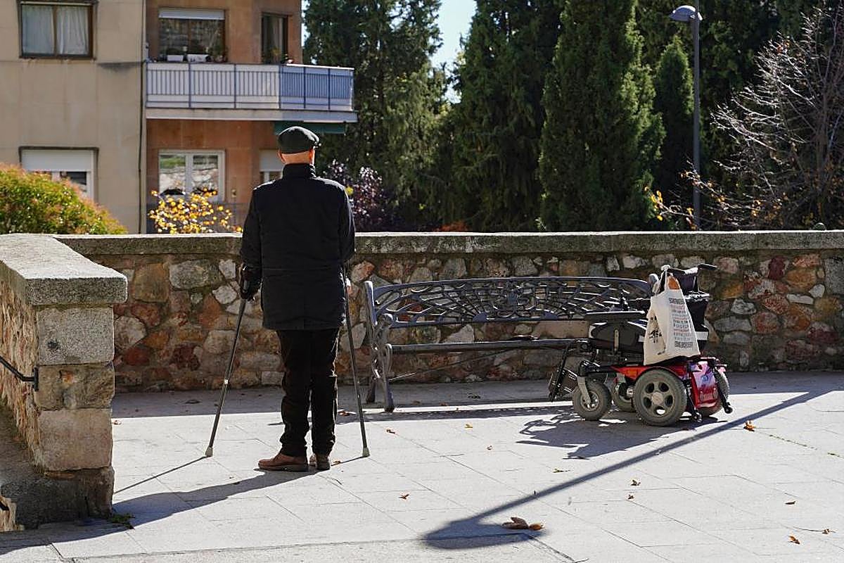 Hombre con muletas al lado de una silla de ruedas