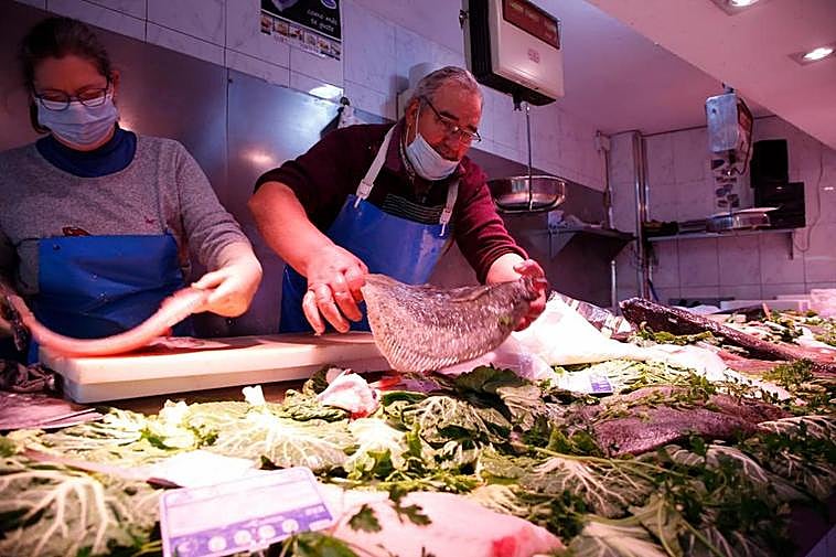 Dos pescaderos preparan sendos pedidos en un establecimiento de la ciudad