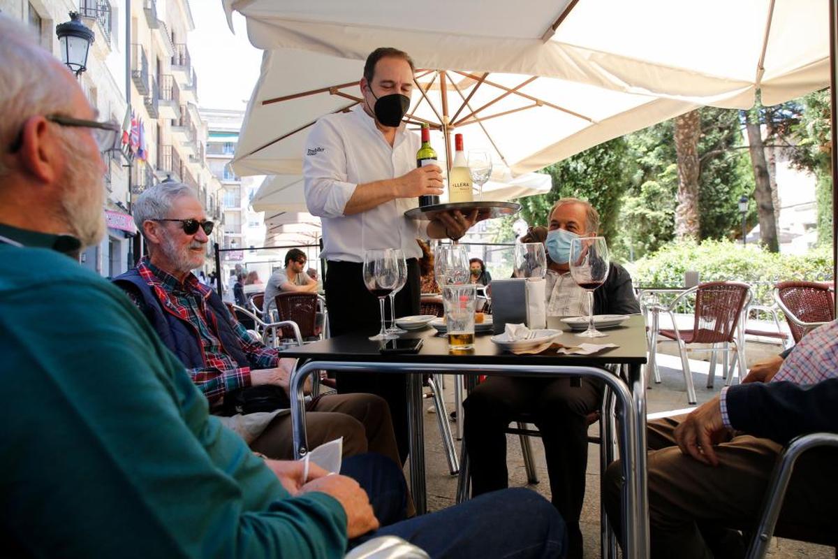 Un camarero atiende a los clientes de la mesa de una terraza en la capital