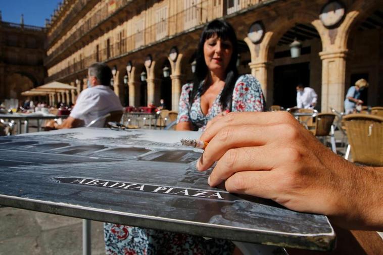 Una persona fumando en una mesa alta de la Plaza Mayor.