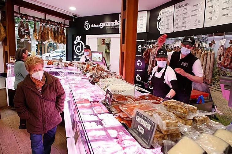 Empleados y clientes de una carnicería, todos con protecciones