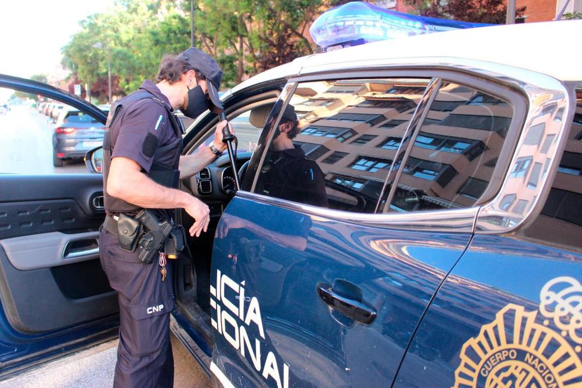 Un agente de la Policía Nacional junto a un coche patrulla.