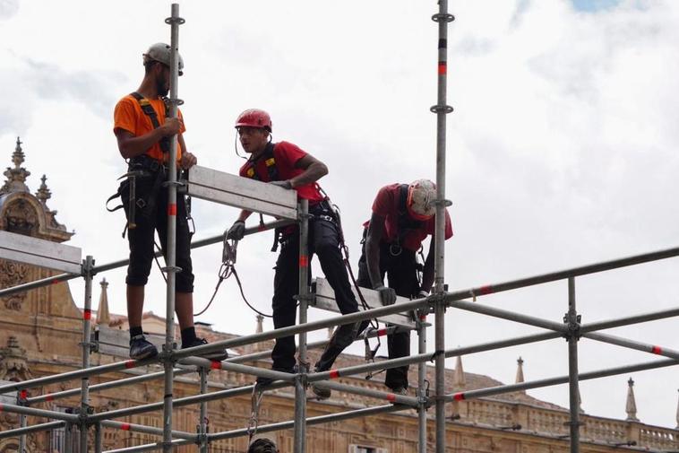 Tres operarios durante el desmontaje de un escenario en la Plaza Mayor.