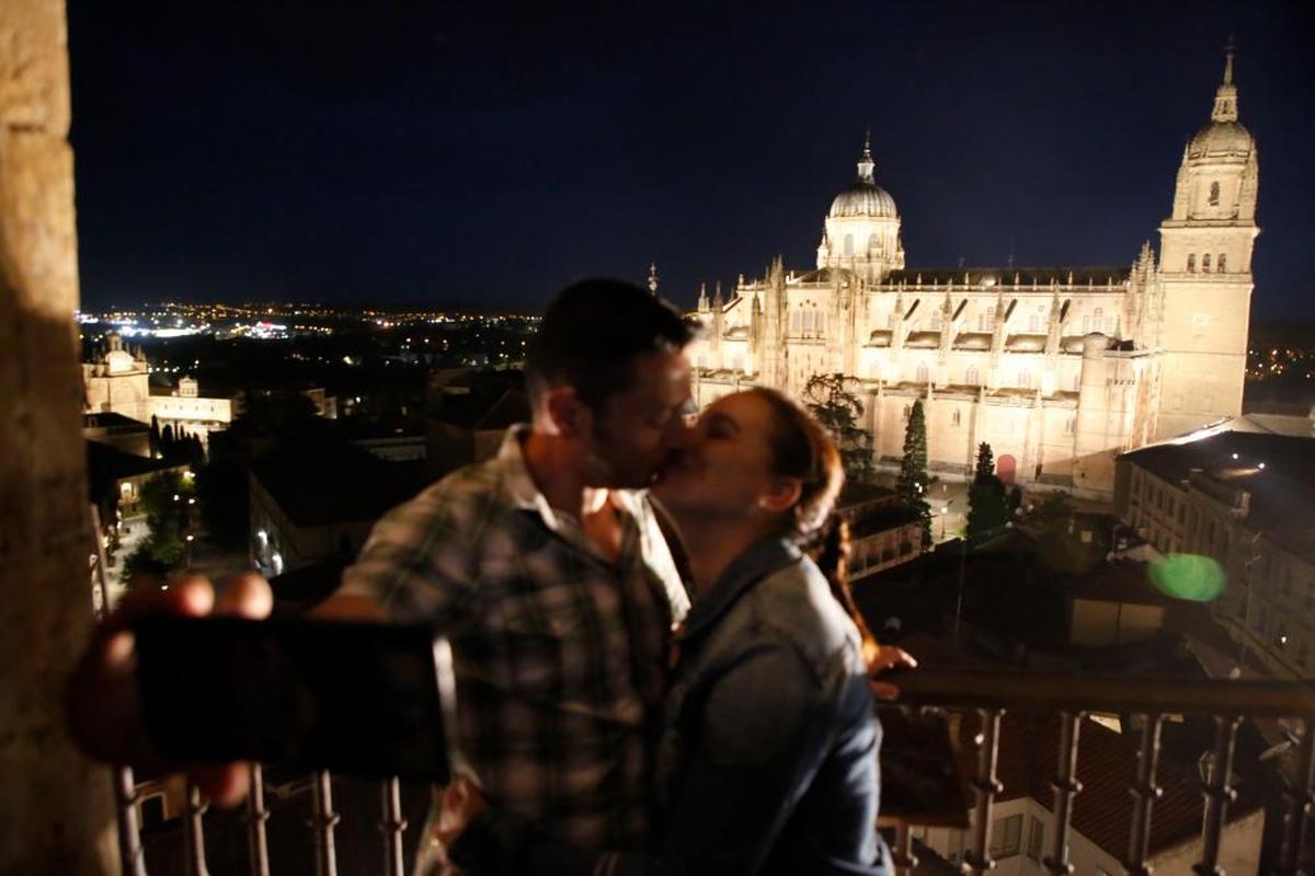 Un pareja se fotografía en las torres de la Clerecía con la Catedral iluminada de fondo