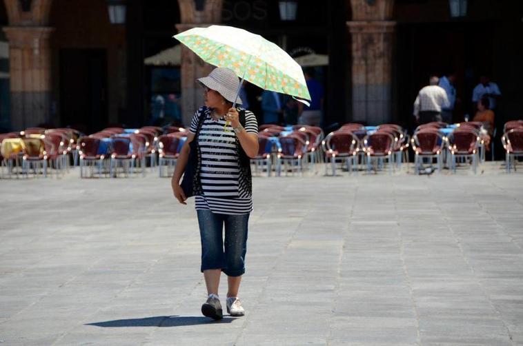 Una mujer se protege del sol en la plaza mayor de Salamanca.