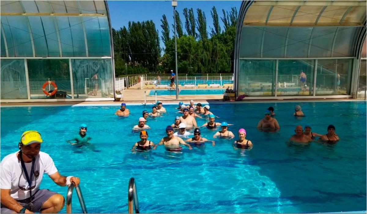 Un nutrido grupo de usuarios disfrutando de una clase de aquagym junto al monitor que la imparte.