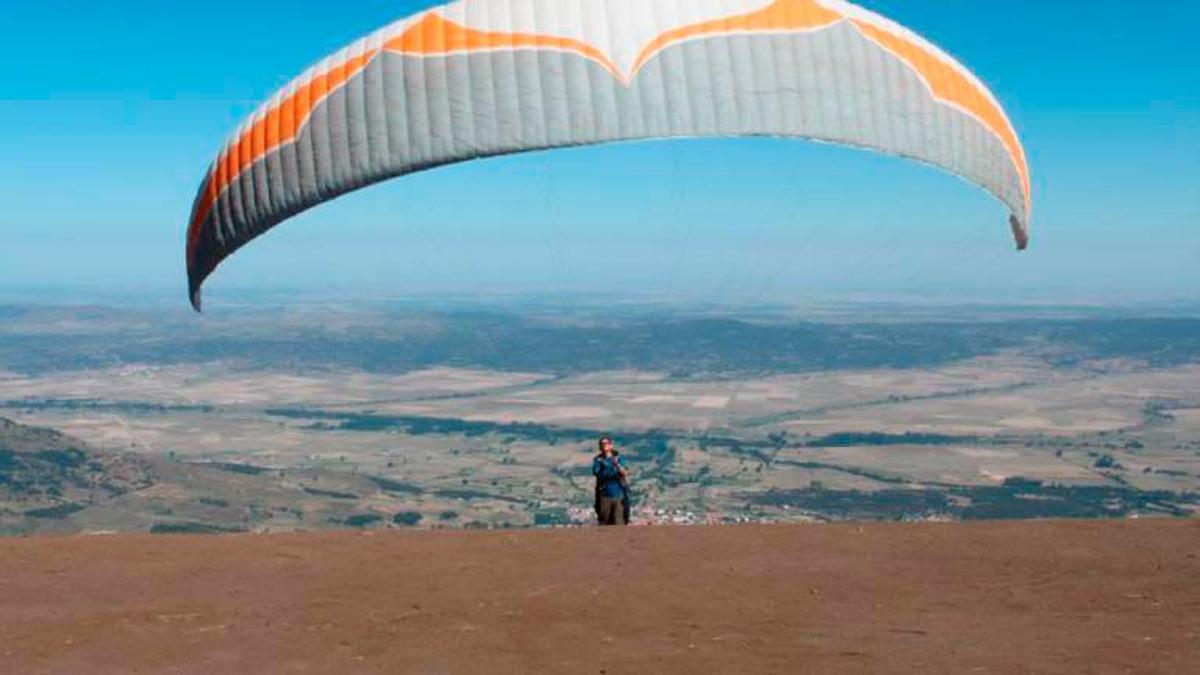 Un parapentista se prepara para volar desde Peñanegra con Piedrahita al fondo.