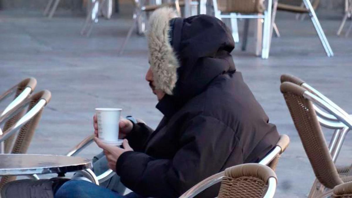 Un ciudadano tomando ayer, bien abrigado, un café en una terraza.