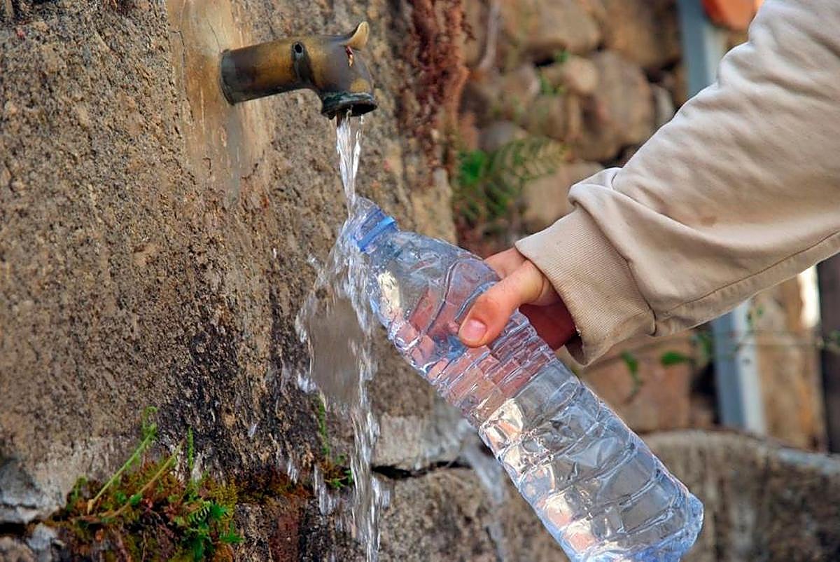 Una persona rellenando agua en una fuente.