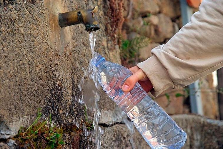 Una persona rellenando agua en una fuente.