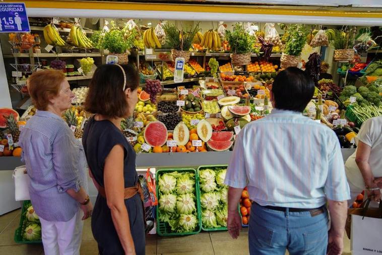 Varios clientes hacen cola para comprar en un puesto del mercado.