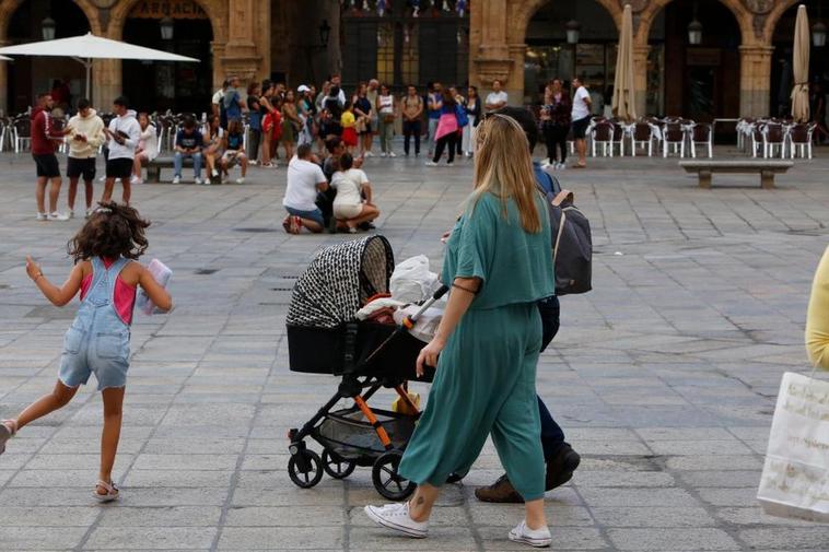 Una pareja con un carrito de bebé paseando por la Plaza Mayor de Salamanca.